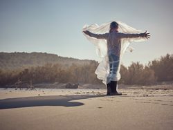 Child caught up in plastic film on sandy beach