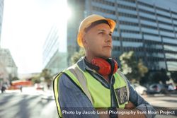 Construction worker looking away thoughtfully in the city in safety gear 0LB8A4