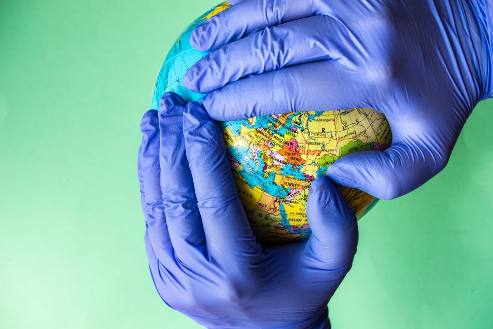 Covid-19 virus concept of hands in latex gloves holding globe