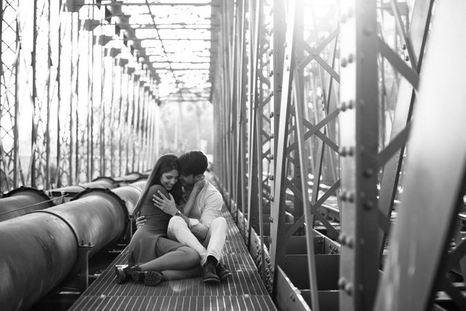 Amorous couple bonding on railway under bridge