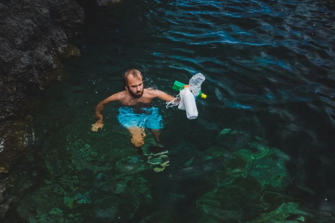Man swimming in water with rubbish