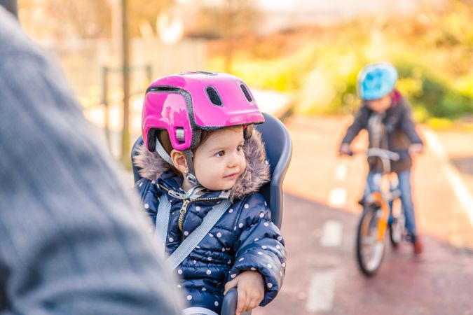 Portrait of observant girl with pink helmet on in bike seat enjoying ride