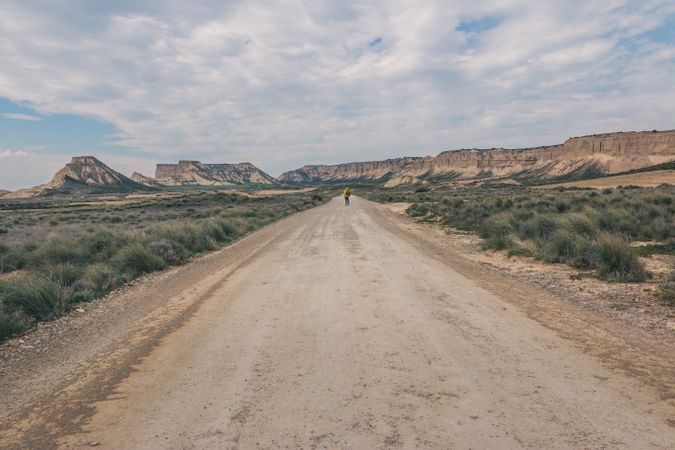 Man standing on road in desert hills