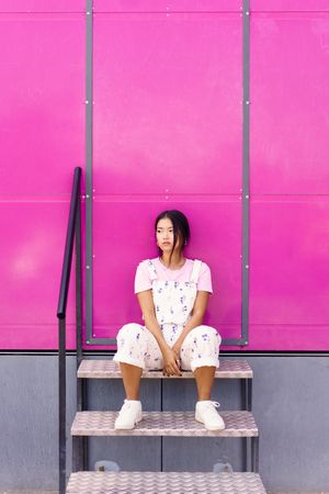 Chinese woman sitting on stairs in front of pink trailer