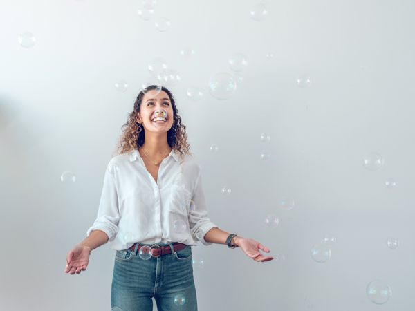 Happy woman looking at falling soap bubbles in amazement