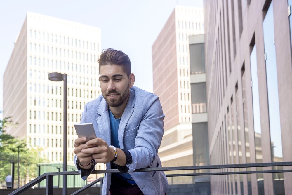 Portrait of Handsome young man smiling checking his mobile phone