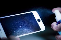 Crop hands cleaning smartphone display