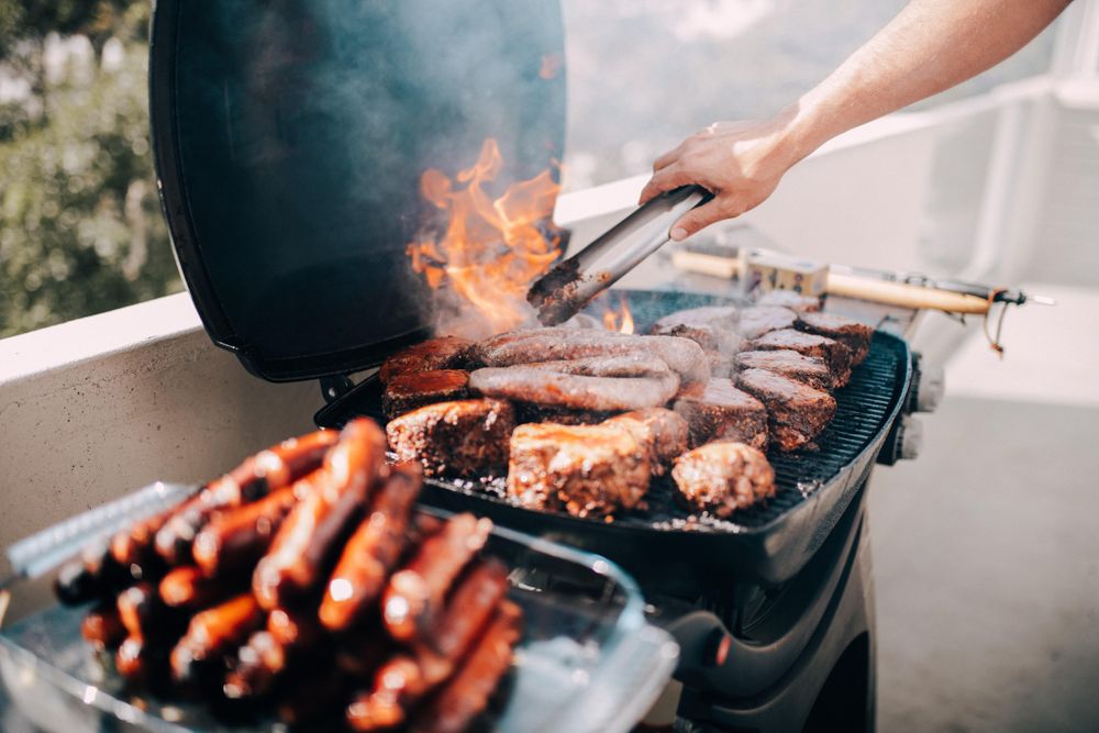 Man with meats on a fiery grill