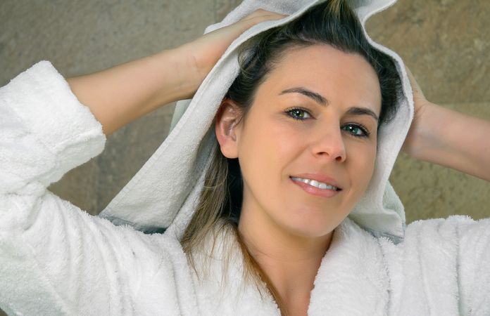 Young woman wiping wet hair with a towel