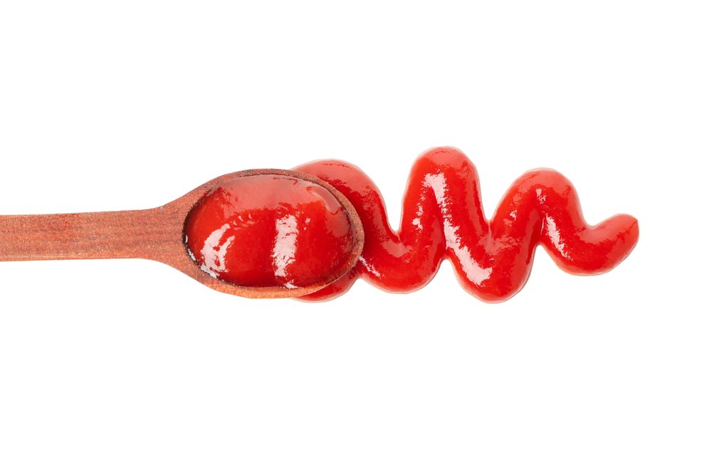 Wooden spoon with tomato sauce isolated on neutral background