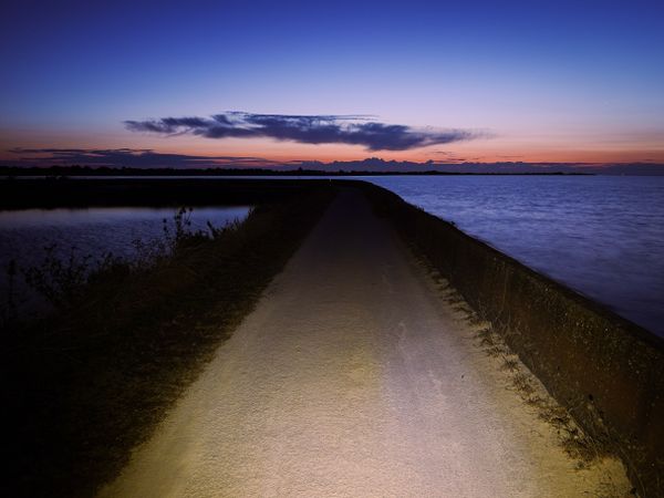 Bike light lighting the path of the dike at twilight