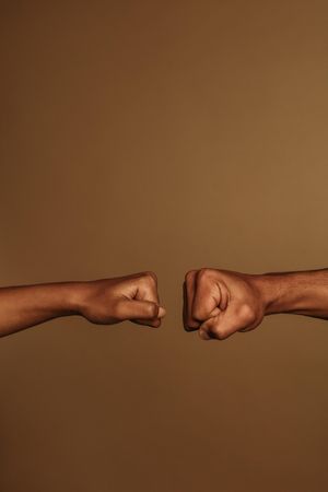 Cropped shot of two fists  isolated on brown background