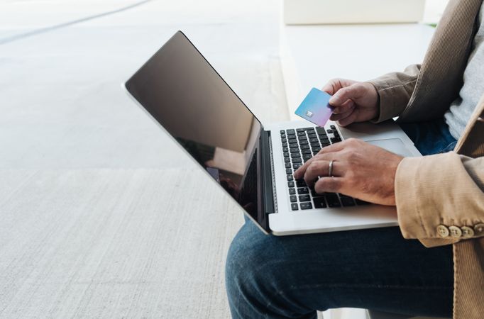 Crop businessman shopping online on street