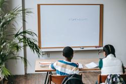 Back view of two students sitting in classroom