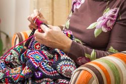 Hands of woman knitting a vintage wool quilt