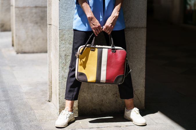 Woman holding colorful computer bag on sunny street