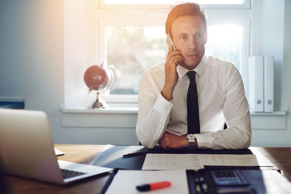 Man in shirt and tie on cellphone in office