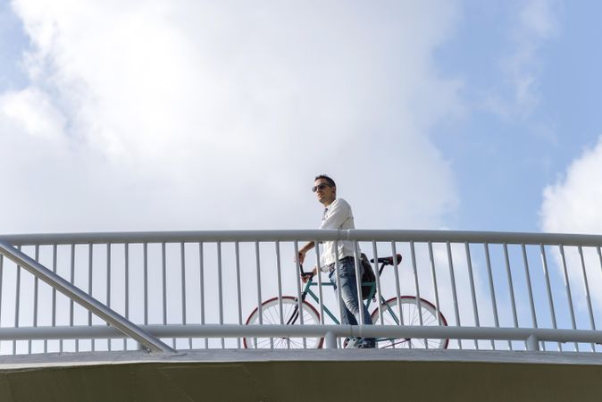 Looking up at male on bike crossing bridge