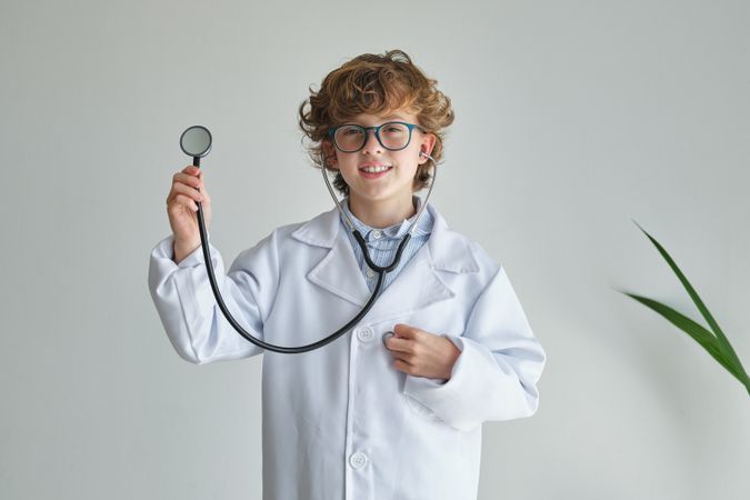 Smiling boy doctor with stethoscope on white background