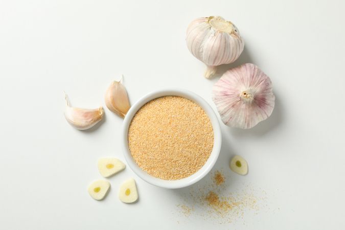 Top view of bowl of garlic powder with bulbs