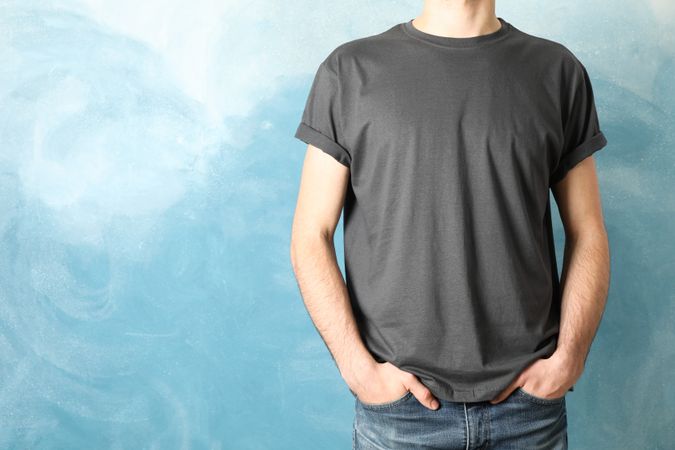 Men in blank grey t-shirt against blue background, space for text