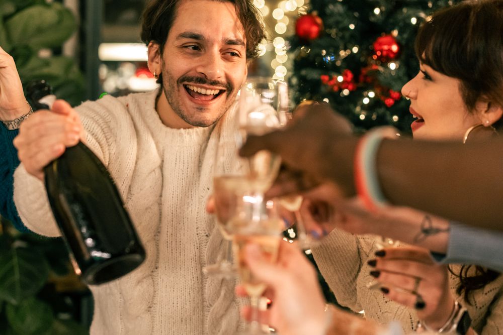Joyful man laughing and toasting with friends at a Christmas party.