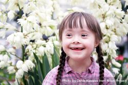 Smiling young girl with Down syndrome outside with spring flowers 4jQqv5