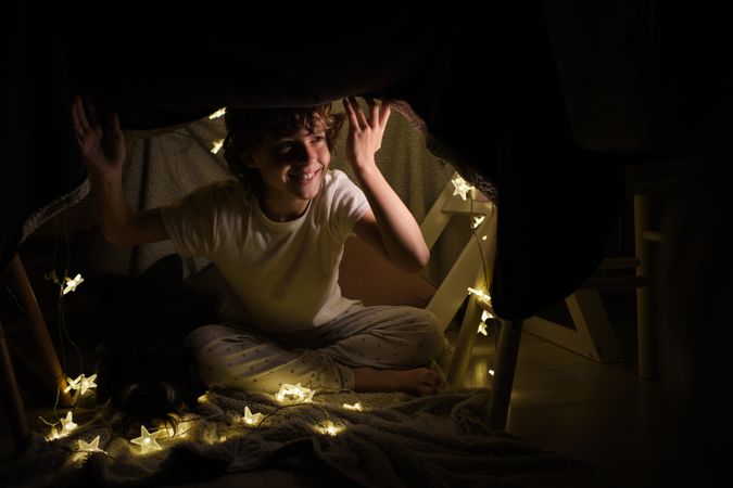 Happy boy sitting in blanket fort
