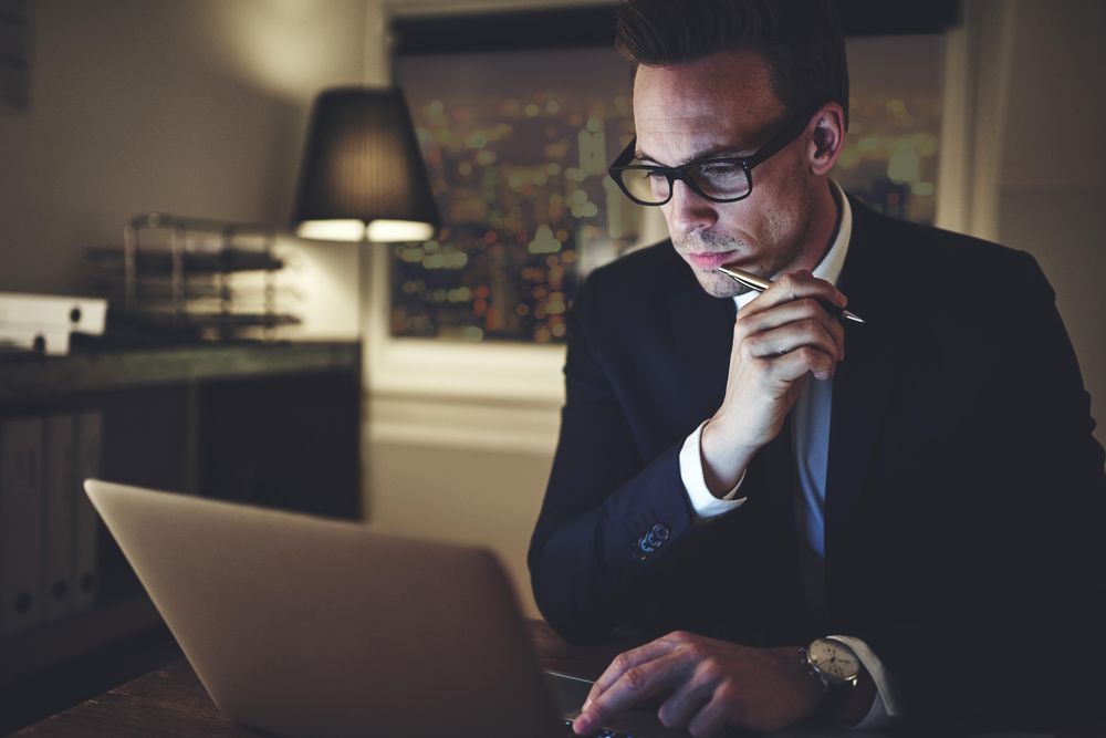 Contemplative man reading something on his laptop