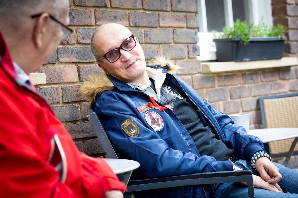 Two older male friends sitting outside and talking