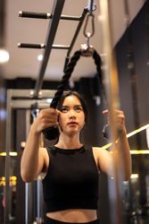 Woman doing Cable Arm Exercises at the Gym, using the Rope Attachment for Triceps Push Down.