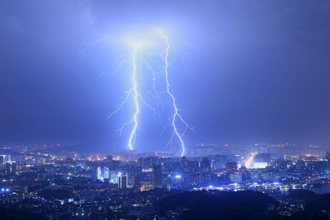 Lightning striking a city during night time