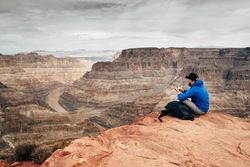 Male having rest on edge of rock and relishing beverage