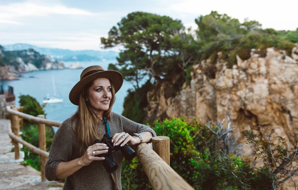 Woman with binocular on coastal walkway
