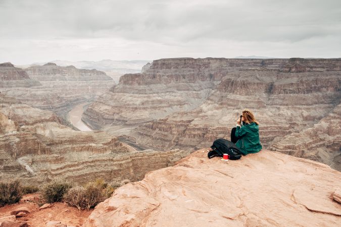 Female relaxing on cliff and admiring picturesque view