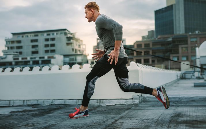 Male athlete doing drag running on rooftop