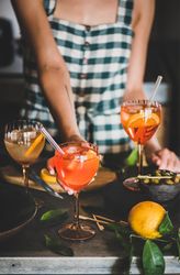 Young woman in checkered dress holding aperitif with orange slices