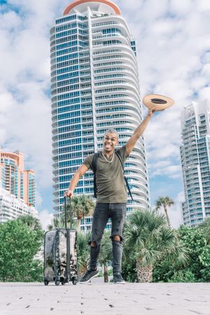 man waving with his hat to say goodbye happy and making a face