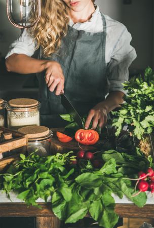 Woman cutting tomato in rustic kitchen