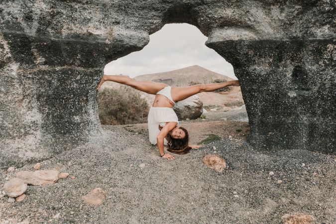 Flexible female doing split in stone arch