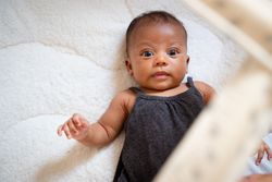 Cute baby girl with huge eyes lying on her back