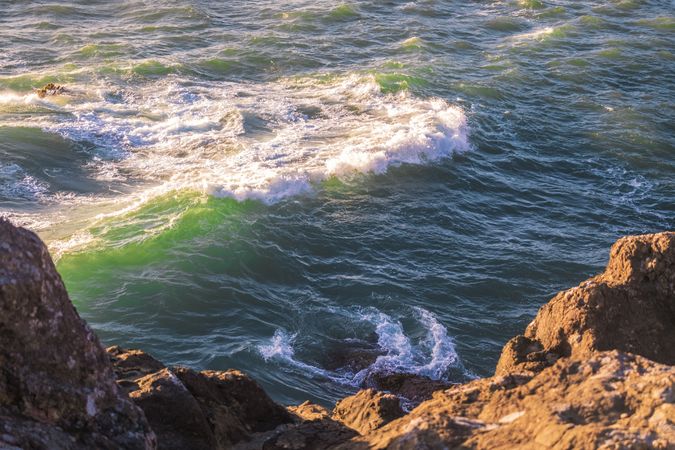 Looking down at water frothing below cliffs