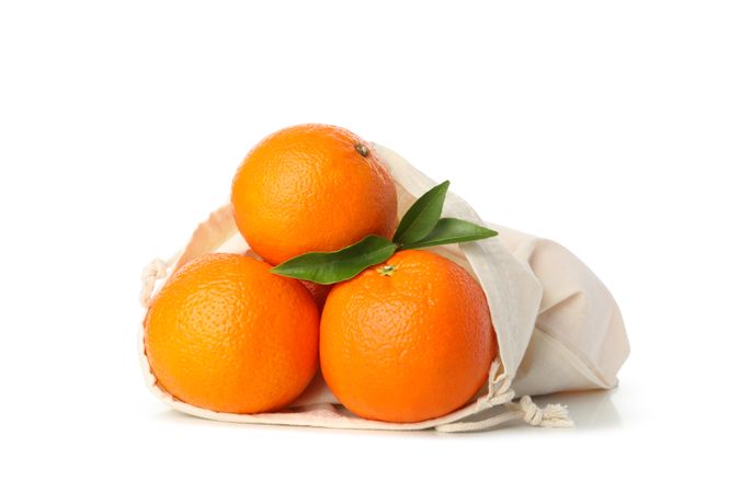 Cotton bag with ripe mandarins isolated on light background