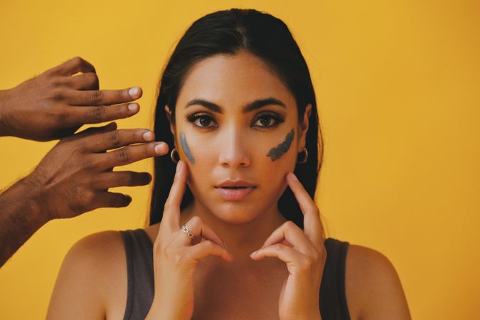 Latina woman with hands outreaching to apply mud mask, copy space