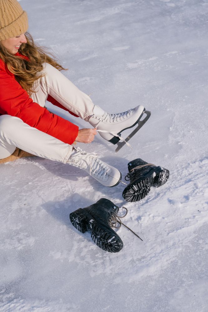 Woman sitting on snow and changing boots