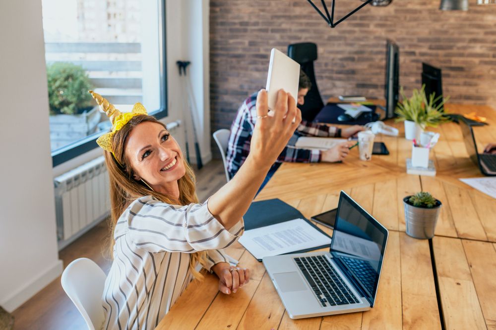 Business woman taking selfie with unicorn headband