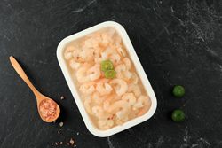 Trey of frozen shrimp with spoon and limes