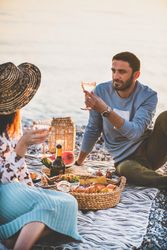 Two people at summer picnic outdoors with man holding glass of wine