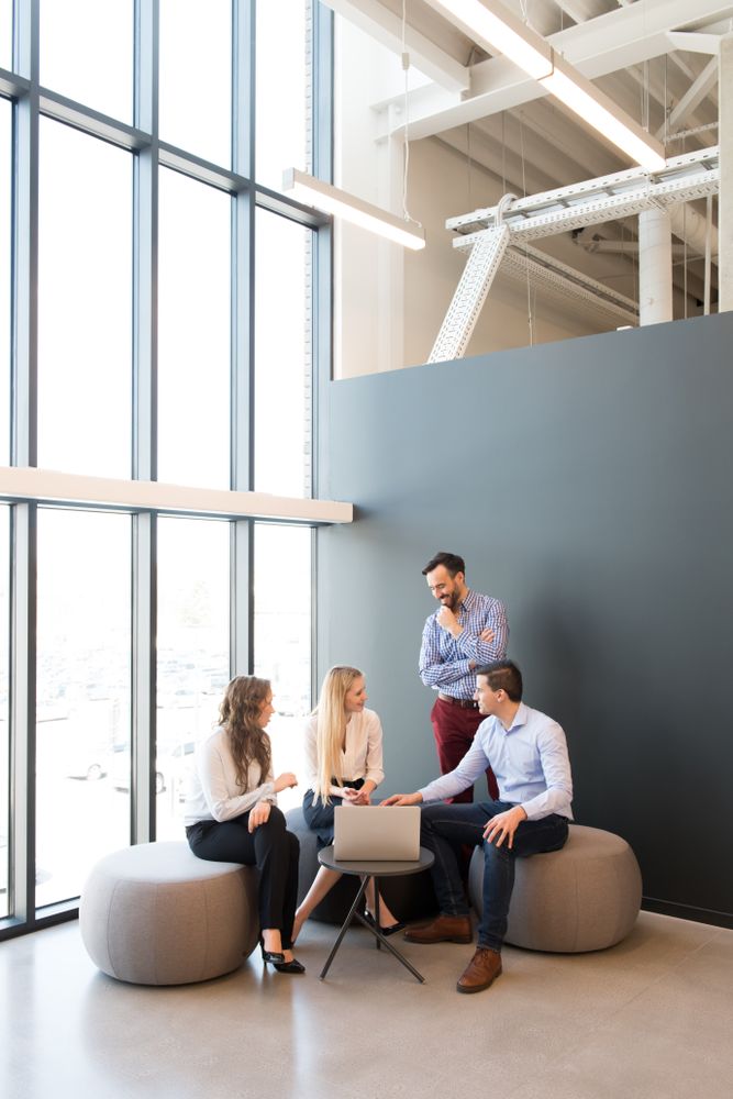 Stylish coworkers gathering around laptop in office