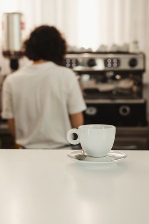 Cup of coffee on counter with barista in background